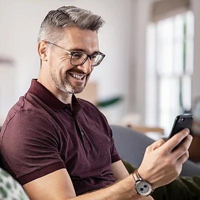Ein Mann nutzt sein Smartphone und erkundigt sich zum Thema Baufinanzierung.
